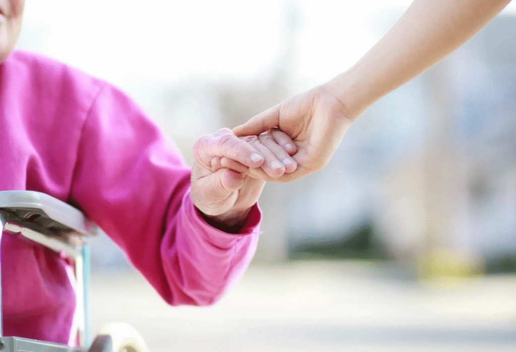 A stock image of a younger person holding the hand of a senior citizen in a seated position.
